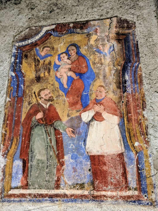Affresco votivo. Due santi in adorazione della vergine Maria con il bambin Gesù. Iscrizione “La Famiglia Cantoni”.