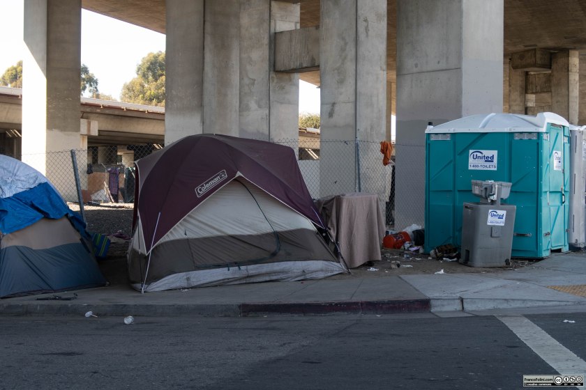 Accampamento di homeless (senzatetto) sotto i cavalcavia dell'autostrada 280 a Oakland, California. Sulla destra si vede un blocco in plastica grigia: si tratta di un distributore di acqua potabile fornito dalla città di Oakland per alleviare le condizione disperate degli abitanti di questo accampamento illegale.